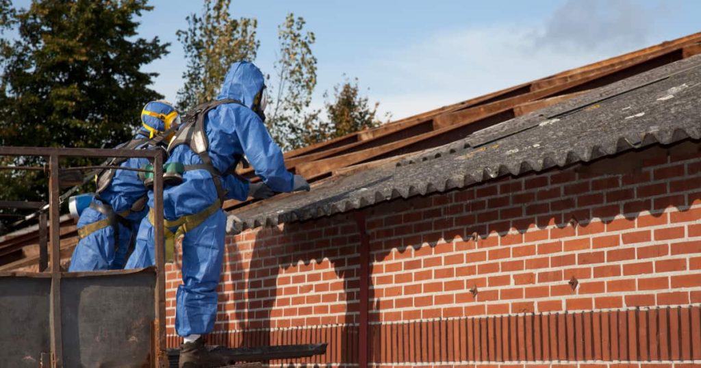 Des ouvriers portant une tenue sécurisée retirent une toiture en amiante