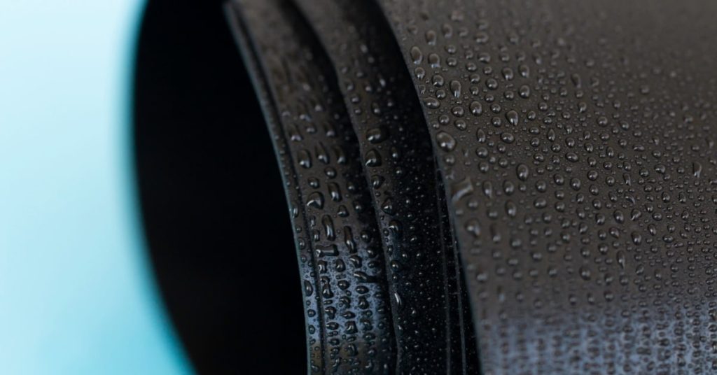 Gouttes d'eau sur un rouleau de caoutchouc noir sur fond bleu ciel