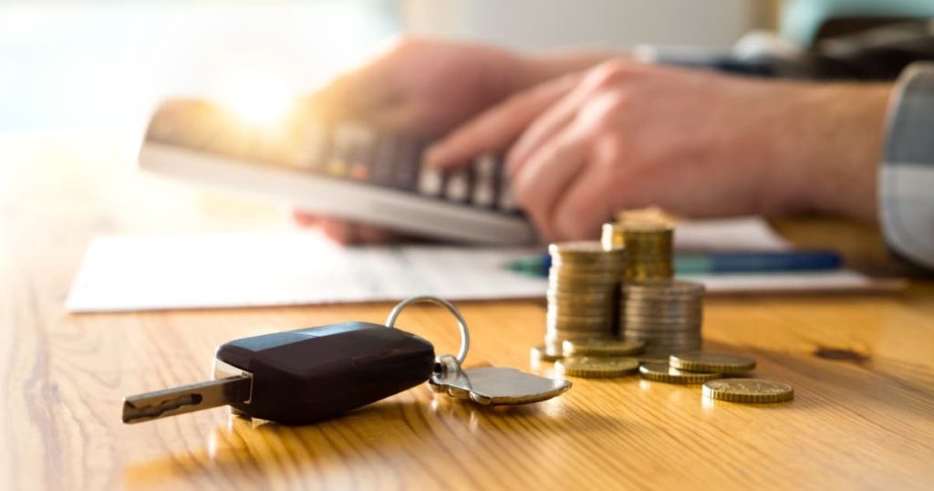 Un homme avec une calculatrice, calcule le prix de son assurance auto