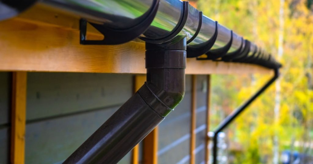 Gouttière noire sur maison en bois