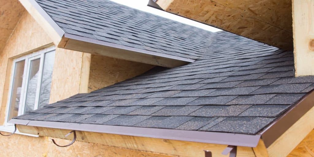 Des tuiles de toiture qui se chevauchent sur une nouvelle maison en bois de construction
