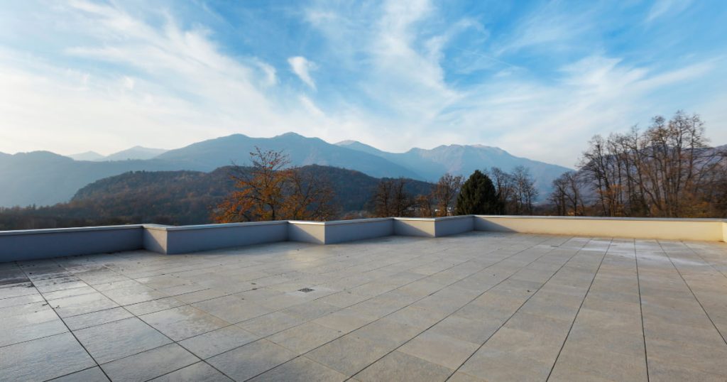 Terrasse sur un toit  plat avec comme revêtement du carrelage avec en fond paysage montagneux 