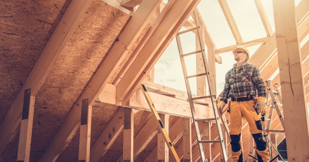 Charpentier dans les combles sur chantier avec charpente en bois
