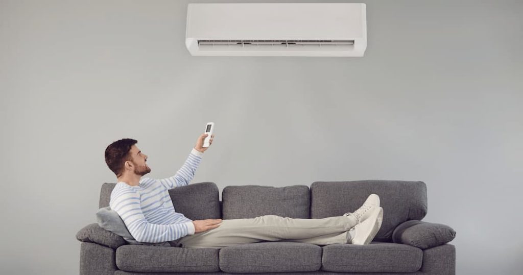 Un homme allongé qui utilise son climatisateur avec sa télécommande