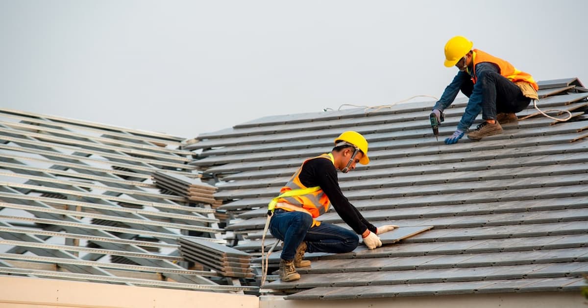 Deux professionnels en train de poser une toiture en ardoise
