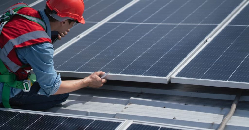 installateur qui installe et oriente un panneau solaire