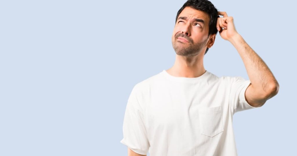 homme au tee shirt blanc qui s'interroge sur un fond bleu