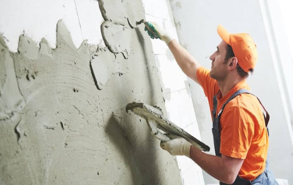 Professionnel qui pose une couche de mortier sur le mur d'une cave