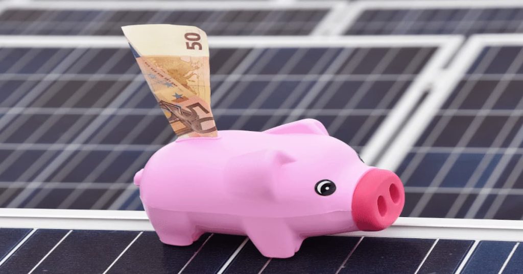 tirelire cochon rose avec un billet dedans, le tout sur des panneaux photovoltaïques