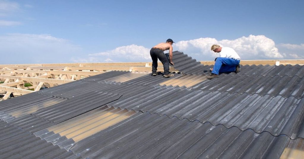 Remplacement d'une toiture en Eternit par deux ouvriers sur une charpente en bois