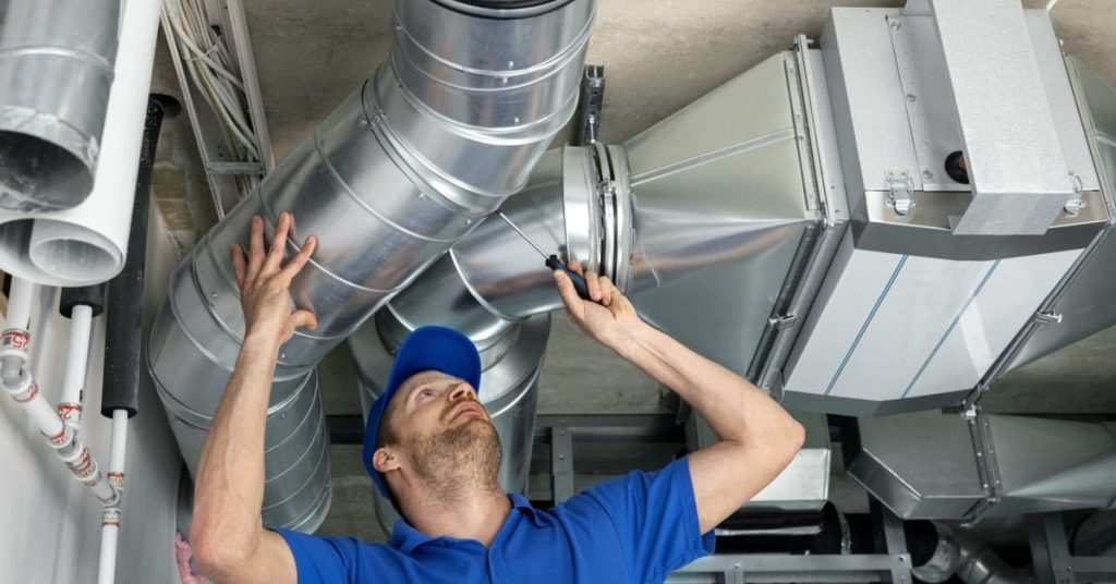 Installateur de ventilation qui répare et fixe un tuyau de ventilation. 