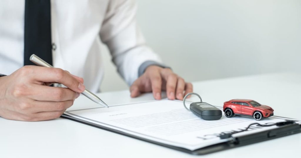 Un homme signe un contrat pour une assurance Auto  