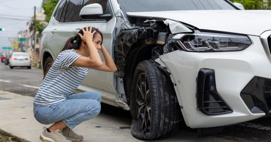 Une femme qui est en état de choc devant sa voiture lourdement accidentée