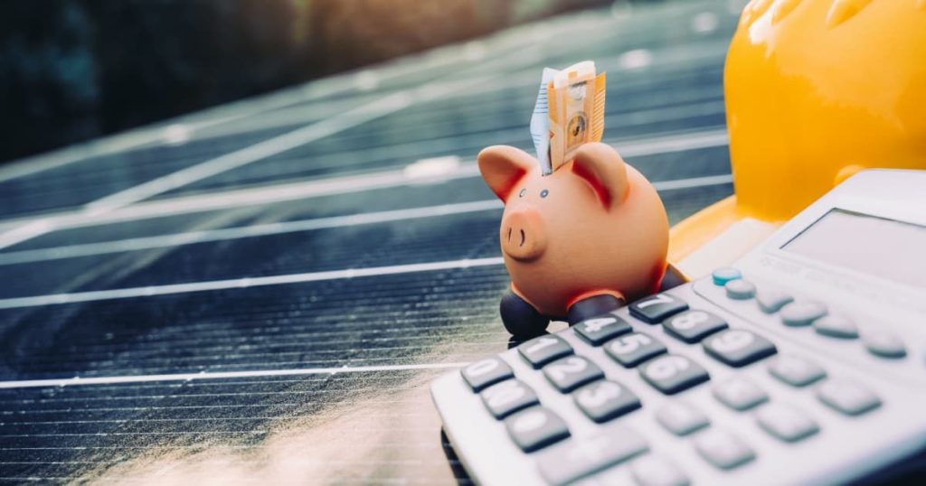 tirelire cochon sur panneaux solaires avec un casque de chantier jaune et une calculatrice 