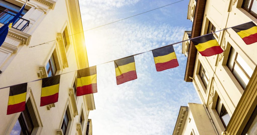 des petits drapeaux belges tiennent sur une corde accrochée entre deux bâtiments