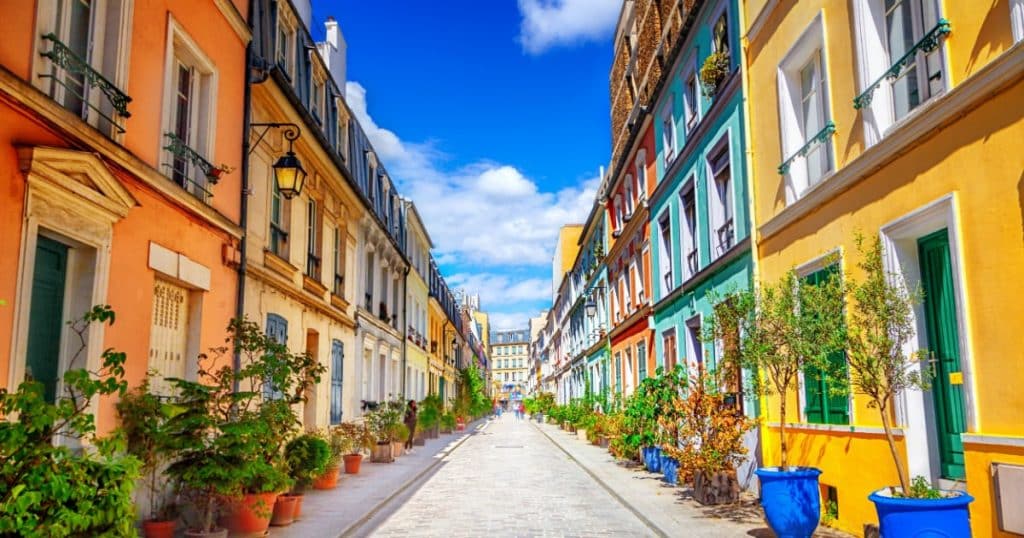 Rue à Paris avec des maisons dont les façades sont toutes colorées de différentes couleurs. 