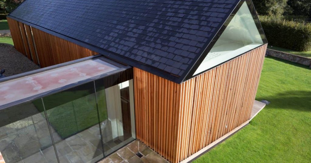 maison en bois au milieu du jardin avec extension de toiture