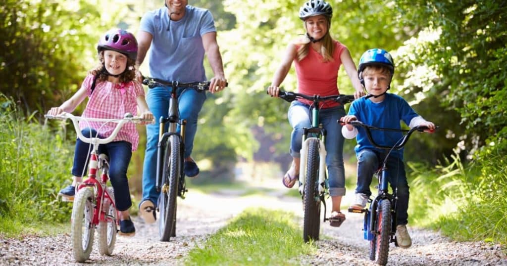 Une famille se balade à vélo dans un bois.