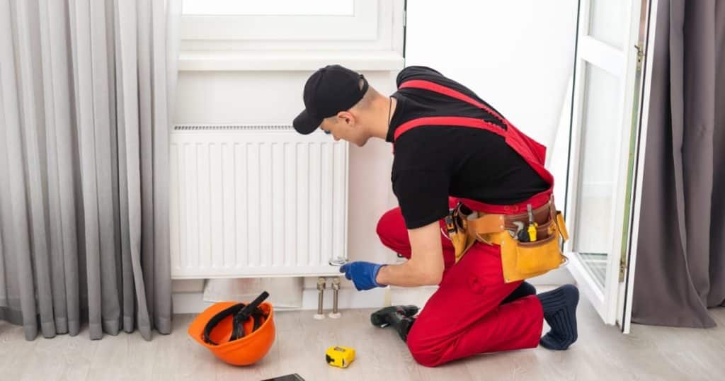 Un installateur raccorde un radiateur dans une maison