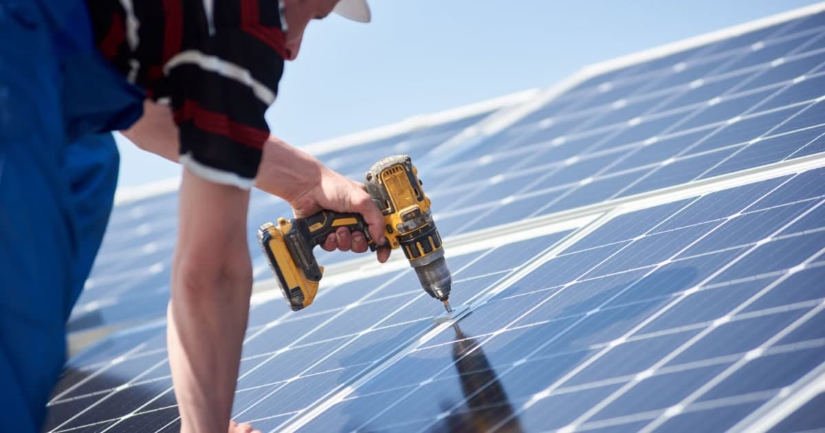 Un artisan fixe des panneaux solaires sur une toiture 