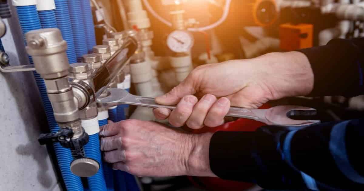 professionnel qui installe pompe à chaleur avec clé a molette