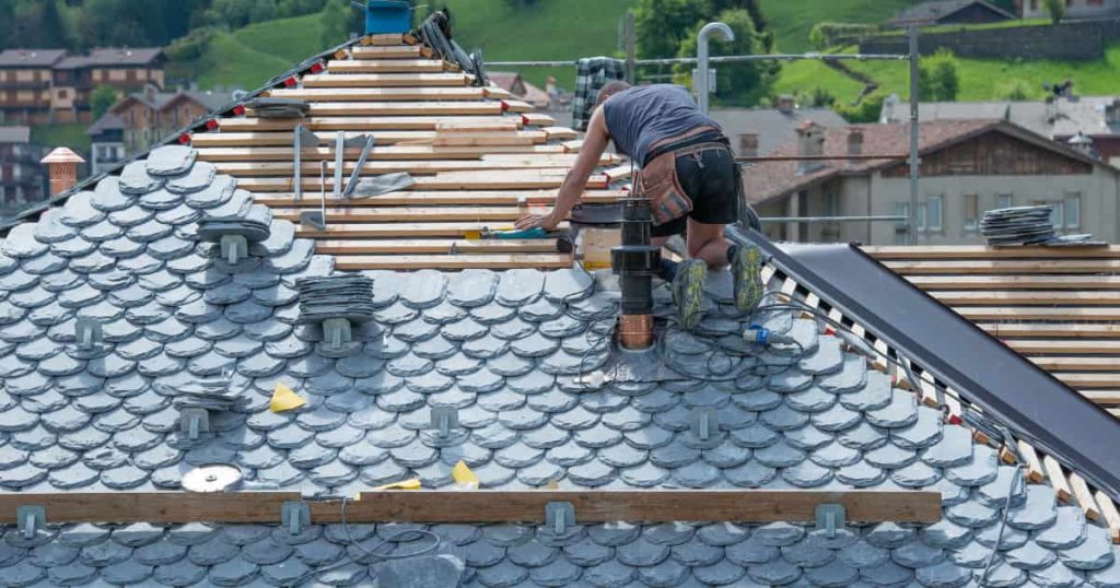 ouvrier remplaçant les tuiles sur un toit