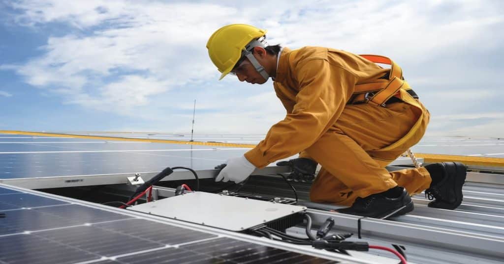 Technicien qui est en train d'installer un onduleur ou réparer sur un panneau solaire.