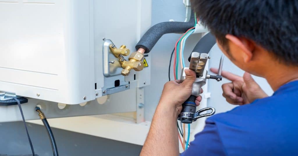 Un professionnel en train de serrer des tuyaux d'une unité extérieure.