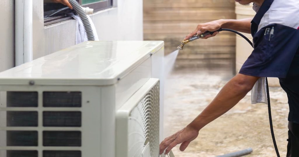 Un technicien est en train d'entretenir une unité extérieur d'un climatiseur fixe