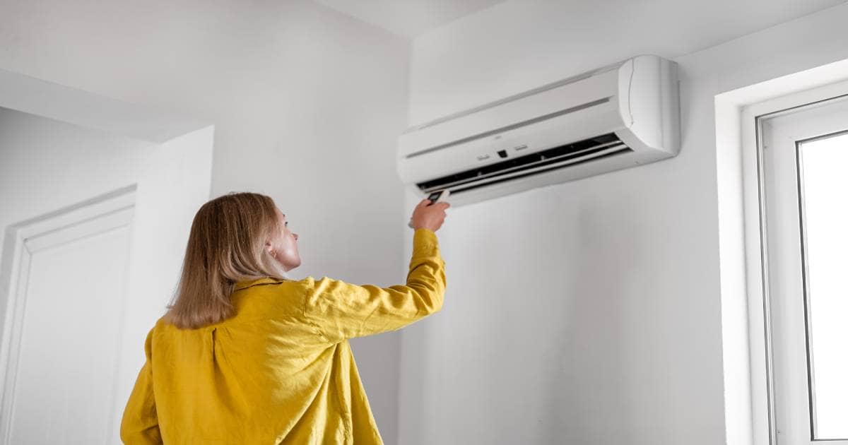 Een jonge vrouw bedient haar airco voor de eerste keer na de installatie.