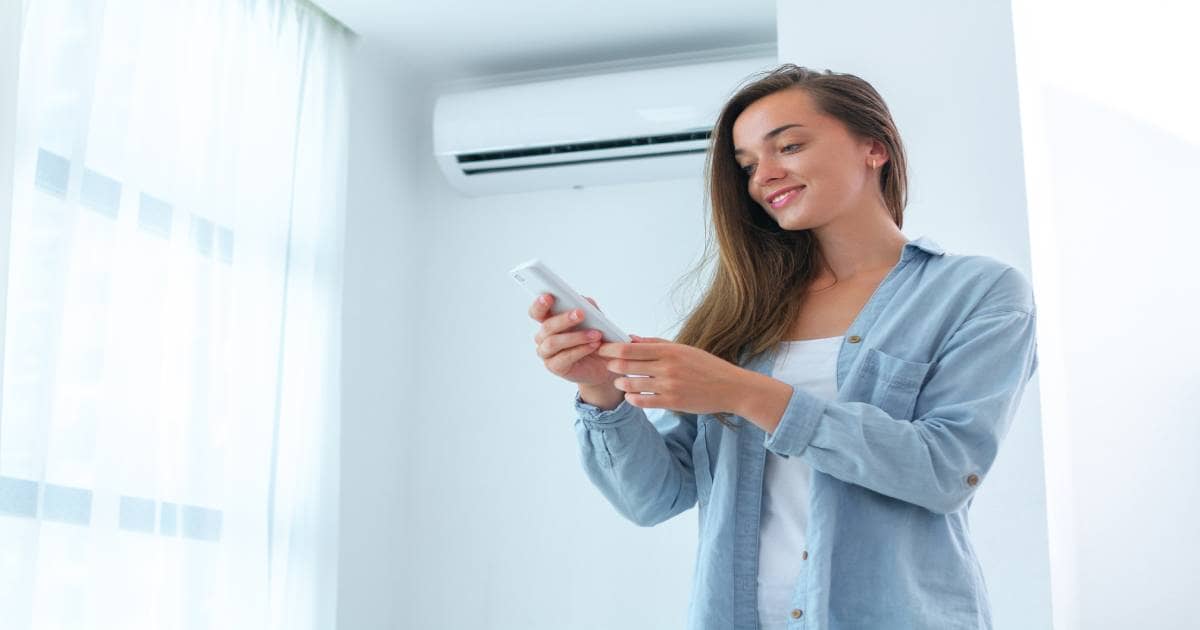 Een jonge vrouw is blij met haar airco die net onderhoud heeft ondergaan.