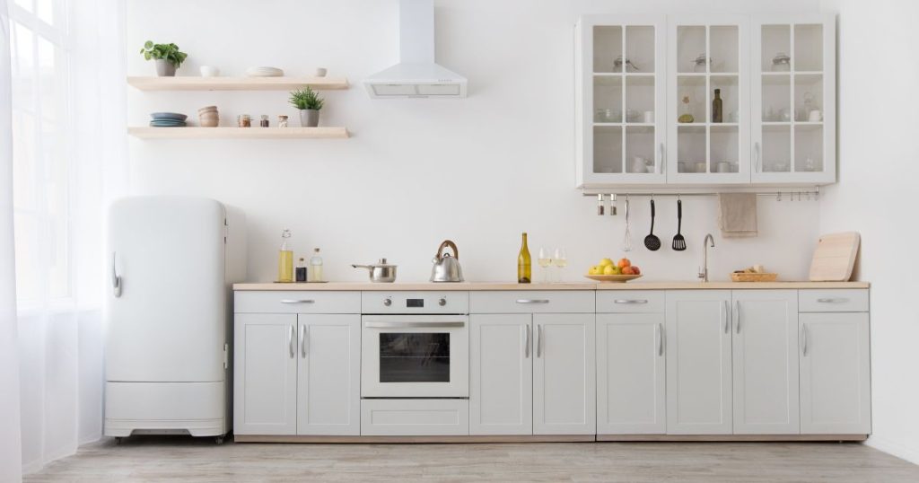 Witte, klassieke keuken met houten wandplanken die servies, plantjes en kruiden dragen 