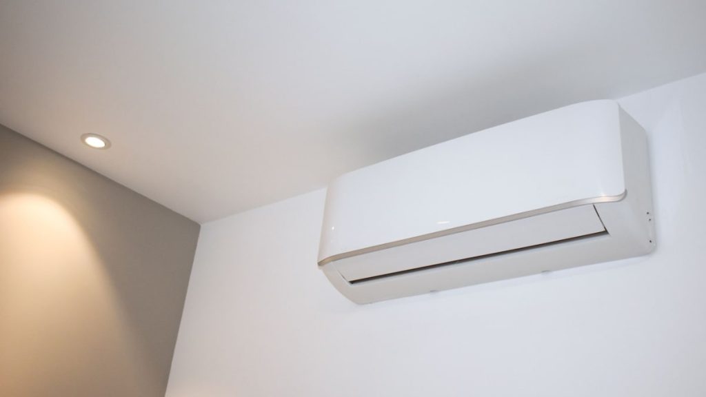 Witte split-unit airco in een woonkamer, tegen een witte binnenmuur. 