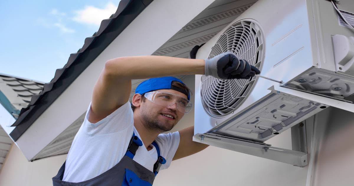 Een erkende airco-installateur monteert de buitenunit aan een huis.