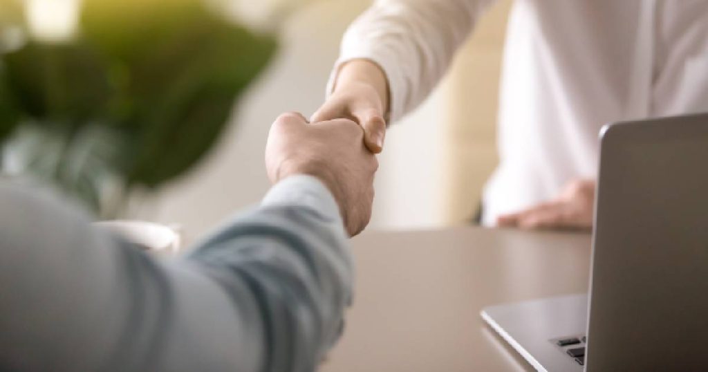 Twee mensen schudden elkaar de hand na het vinden van een overeenkomst omtrent de prijs voor een omnium verzekering.