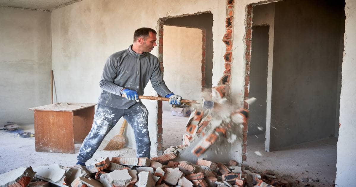 Een man gebruikt een sloophamer om zijn woning te slopen. Ook als doe-het-zelver kan hij gebruik maken van de sloop- en heropbouwpremie.