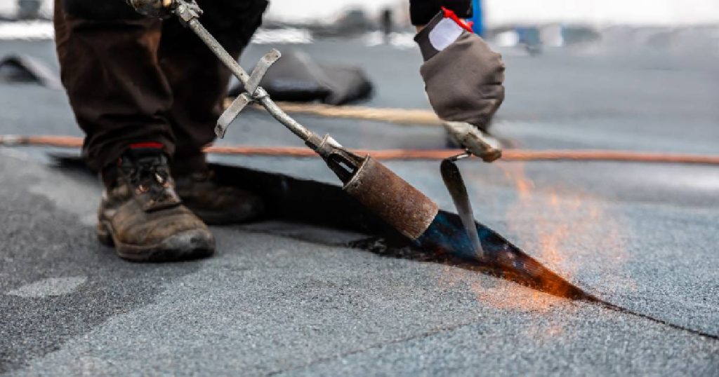 Een dakwerker brengt roofing, bitumen of dakleer aan met een brander. Roofing is een goedkoper maar minder duurzaam alternatief op EPDM dakbedekking.