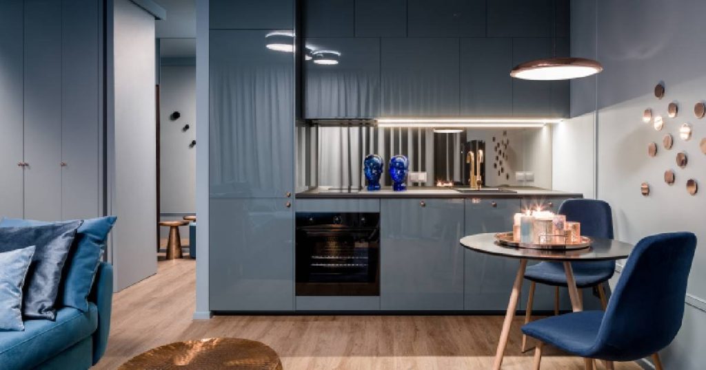 Een moderne blauwe keuken met hoogglanzende keukenkasten op een houten vloer.