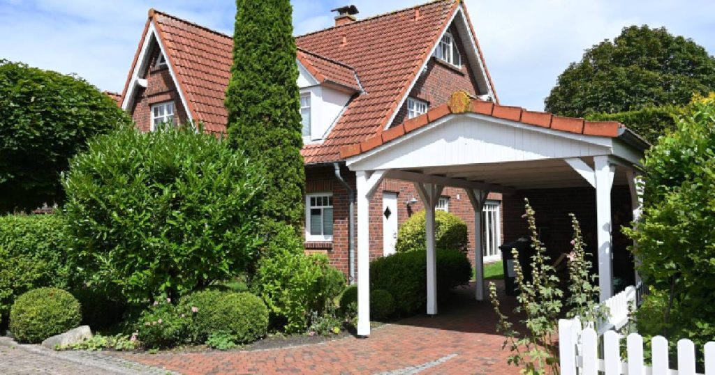 Een klassieke witte carport met dakpannen en een tegelvloer.