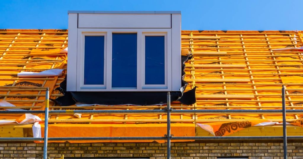 Een dak dat de bewoners lieten verhogen met een budgetvriendelijke, kunststof dakkapel. De rest van het dak wordt opnieuw geïsoleerd en bekleed: de pannenlatten en tengellatten liggen alvast klaar, met daaronder het oranje onderdak.