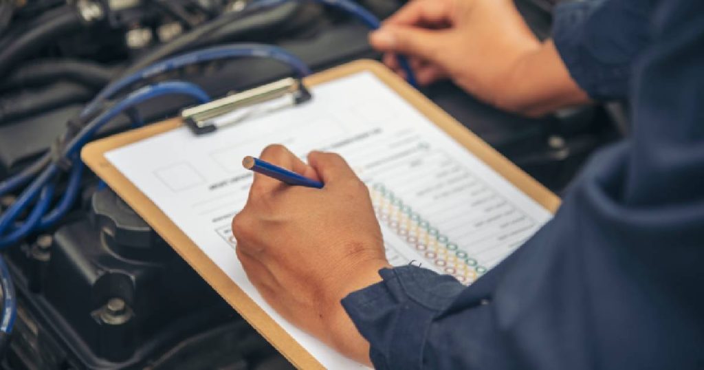 Na het voorleggen van het gelijkvormigheidsattest gaat een technieker aan de slag met de keuring van een auto. Hij draagt een blauwe overal en gebruikt een klembord, keuringsdocument en potlood om te rapporteren over de controle van de wagen.