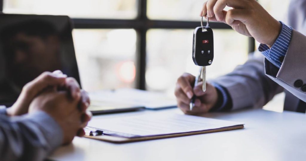 De verkoop van een auto: een persoon in zakelijke kledij geeft de autosleutels en het gelijkvormigheidsattest aan de koper.