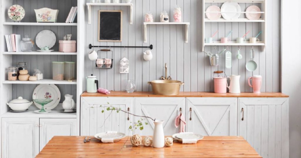 Een goedkope keuken in landelijke stijl met kleurrijke accenten, houten kasten, een houten tafel en een koperen spoelbak.