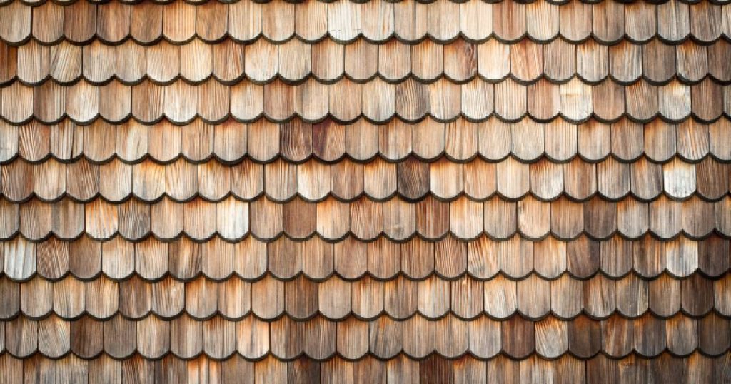 Een dak van een tuinhuis waarop de eigenaars houten dakshingles hebben laten plaatsen.