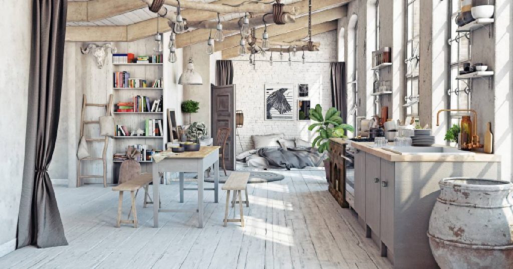 Een lichtgrijze open keuken in een gezellige loft. Er werd gekozen voor een lichte, witgrijze houten plankenvloer, grijze keukenblokken met houten aanrechtblad en een gezellige tafel met bankjes.