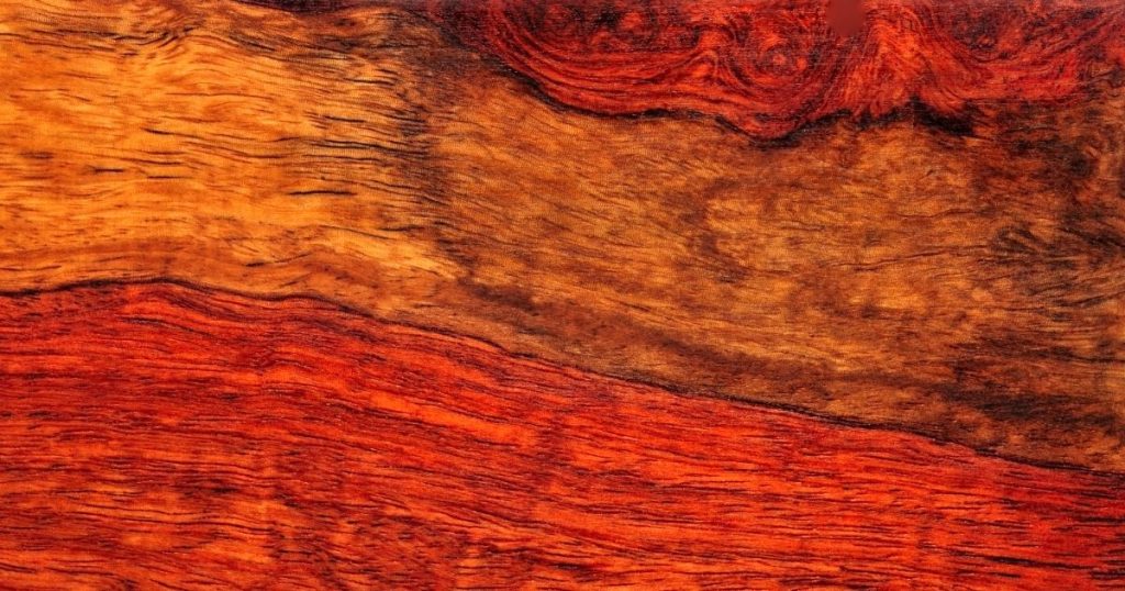 Detailbeeld van mahonie hout met een dieprode kleur, ideaal voor het bouwen van een trap met luxueuze uitstraling. 