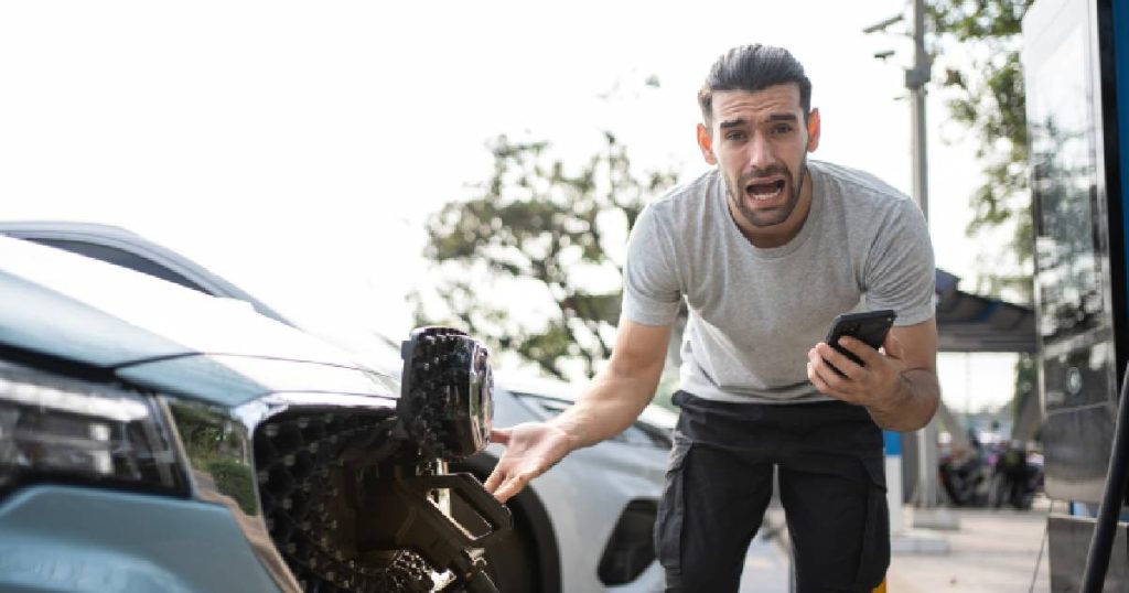 Er durft al wel eens iets verkeerd gaan. De man met baard, grijze t-shirt en donkere broek reageert verontwaardigd als zijn elektrisch voertuig niet kan opgeladen worden. Heeft de laadpaal een reset nodig?