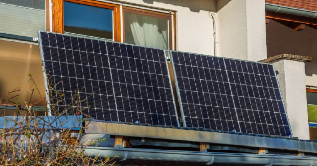 Twee plug and play zonnepanelen op het terras of balkon van een appartementswoning. De panelen zijn met een stekker verbonden met een stopcontact.