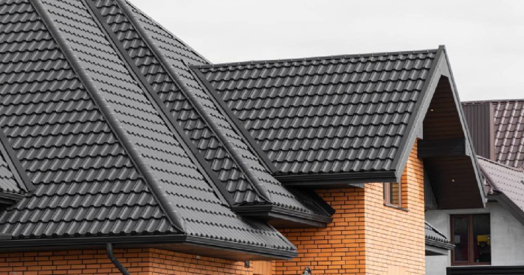 Een moderne woning met oranje bakstenen gevel en dak met zwarte, glanzende keramische dakpannen. 