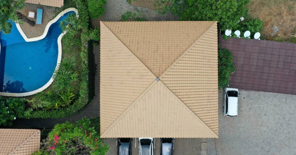 Bovenaanzicht van een woning waarop de eigenaars een puntdak of tentdak lieten plaatsen. Het dak is afgewerkt met lichtbeige dakpannen.